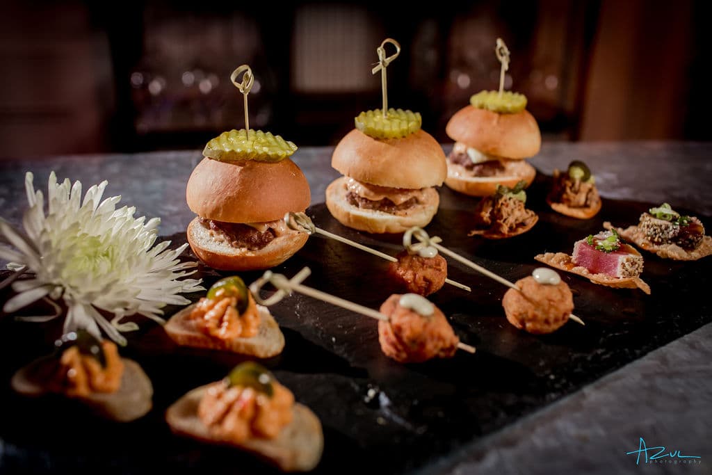 A slate board of elegant late night wedding snacks including mini sliders and bite-sized appetizers — Photo by Azul Photography