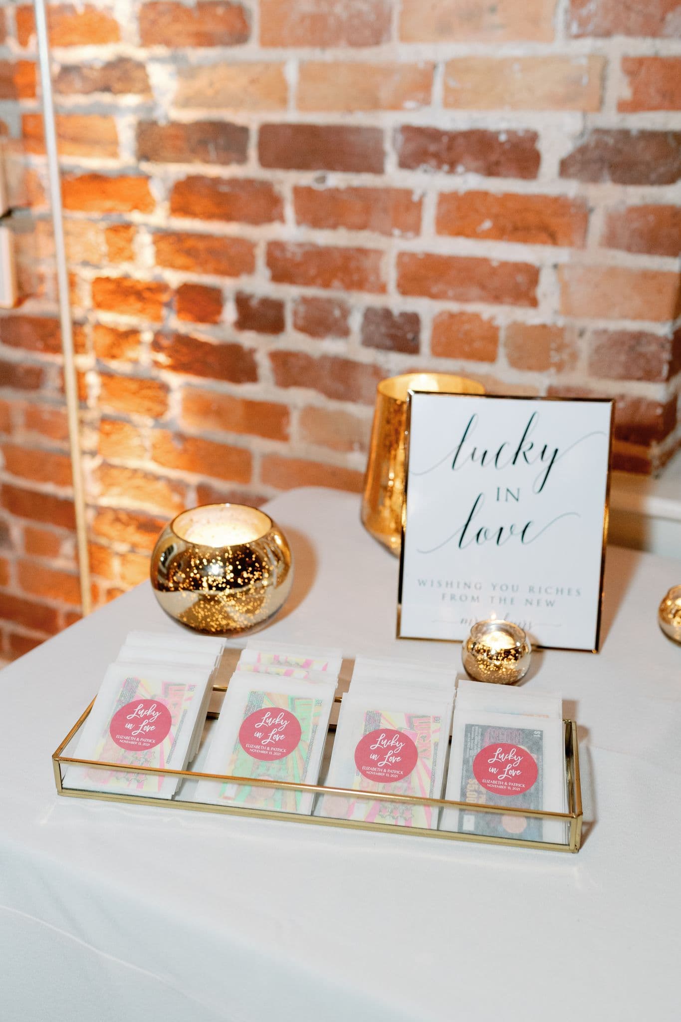 Lucky in Love lottery ticket wedding favors displayed on a gold tray with candlelight — Photo by Megan Travis Photography