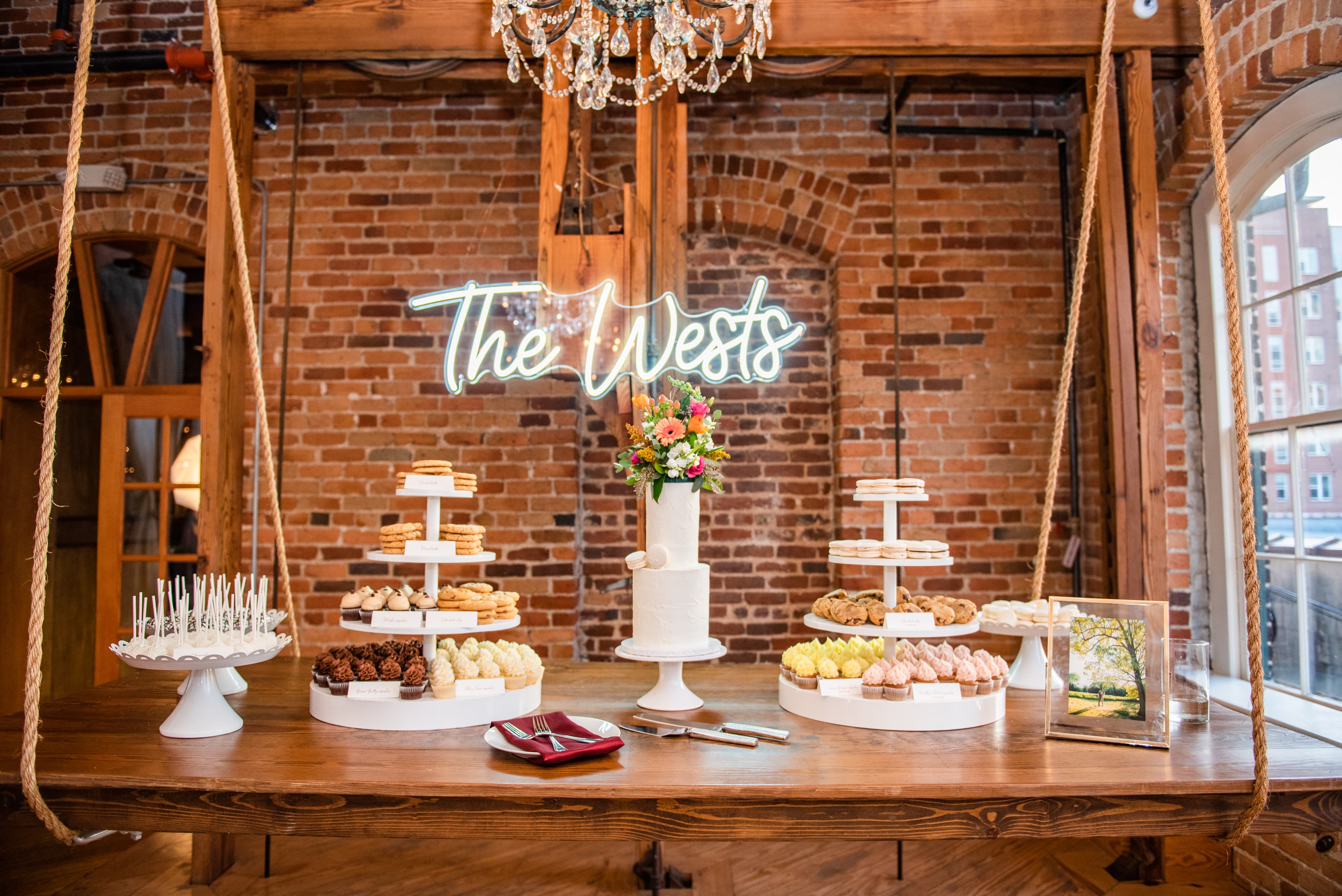A neon sign reading 'The Wests' above a dessert table at a wedding reception — Photo by Lacey Gabrielle Photography